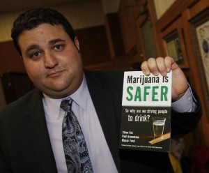 MasonTvert, communications director of the Marijuana Policy Project, holds up a 2010 book which he co-authored, "Marijuana is Safer: So why are we driving people to drink?"  (AP Photo/David Zalubowski)