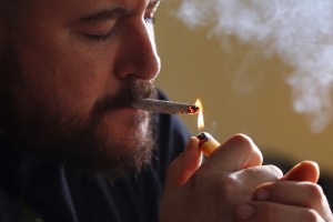 In this photo made Friday, Nov. 21, 2014, former U.S. Marine Sgt. Ryan Begin smokes medical marijuana at his home in Belfast, Maine. Begin had endured 35 surgeries after having his right elbow blown off by a roadside bomb in 2004. He is a proponent of legalizing pot for recreational use and allowing individual citizens the right to grow six plants. (AP Photo/Robert F. Bukaty) Date : November 21,