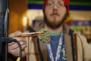 Sales associate Matt Hart uses a pair of chopsticks to hold a bud of Lemon Skunk, the strain of highest potency available at the 3D Dispensary, on Friday, Dec. 19, 2014, in Denver. While polls show more voters favoring the legalization of marijuana, law enforcement officials in Nebraska and Oklahoma have asked the U.S. Supreme court to end Colorado's legalized pot experiment. (AP Photo/David Zalubowski)