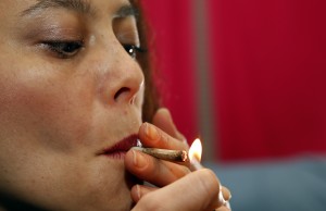 Rica Madrid poses for a photograph as she smokes pot in her home on the first day of legal possession of marijuana for recreational purposes, Thursday, Feb. 26, 2015 in Washington. Democratic Mayor Muriel Bowser defied threats from Congress by implementing a voter-approved initiative on Thursday, making the city the only place east of the Mississippi River where people can legally grow and share marijuana in private. (AP Photo/Alex Brandon)