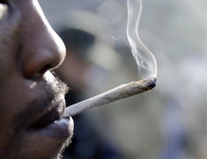 A man smokes a marijuana cigarette as a large group gathered near the New Jersey Statehouse to show their support for legalizing marijuana Saturday, March 21, 2015, in Trenton, N.J. Several people were openly smoking the drug during the rally, but none were arrested. (AP Photo/Mel Evans)
