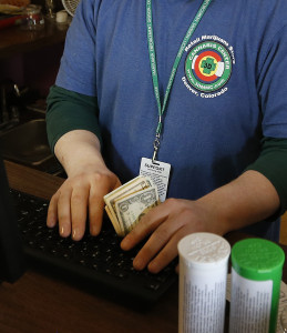 An employee works the register, receiving cash for retail marijuana at 3D Cannabis Center, in Denver. On Thursday, April 9, 2015, a Federal Reserve Bank official met with Marijuana business owners in Colorado about their problems accessing banking services. The closed-door meeting in Denver was arranged by two Colorado congressmen who have tried unsuccessfully to pass laws expanding banking access for the marijuana industry.(AP Photo/Brennan Linsley, file)