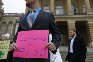 Logan Edwards, a Marine veteran living in Davenport, Iowa, and Denver, holds a sign showing his support for cannabis for sufferers of post traumatic stress disorder Tuesday, April 7, 2015, outside the State Capitol in Des Moines, Iowa. (AP Photo/The Des Moines Register, Michael Zamora) 