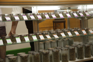 An employee at the medical marijuana dispensary Kaya Shack puts away jars of marijuana flowers on the dispensary's shelves in Portland, Ore. On July 1, recreational marijuana in Oregon is legal, but it's likely customers won't be able to buy the pot at medical dispensaries until October 1. (AP Photo/Gosia Wozniacka)