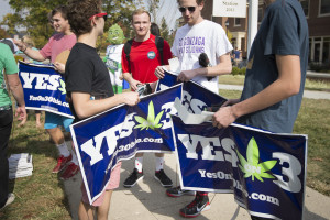 College students collect lawn signs at a promotional tour bus from ResponsibleOhio, a pro-marijuana legalization group, at Miami University, Friday, Oct. 23, 2015, in Oxford, Ohio. A ballot proposal before Ohio voters this fall would be the first in the Midwest to take marijuana use and sales from illegal to legal for both personal and medical use in a single vote. (AP Photo/John Minchillo)